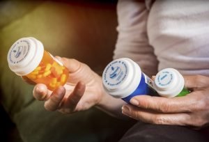 Woman examining medication treatment, several boats in the hand, conceptual image