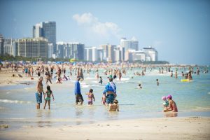 Crowds of people enjoy the sea and sand of South Beach on a hot