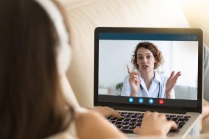Laptop monitor view over woman shoulder, girl in headphones listens female therapist, medic gives recommendation how protect people during corona virus ncov epidemic outbreak pandemic disease concept