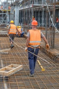 Construction workers carrying heavy steel bar at construction site. Selective focus.