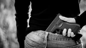 A woman hidden a gun the back. - violence and crime concept.