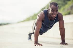 Portrait of a young black man doing push ups at the beach